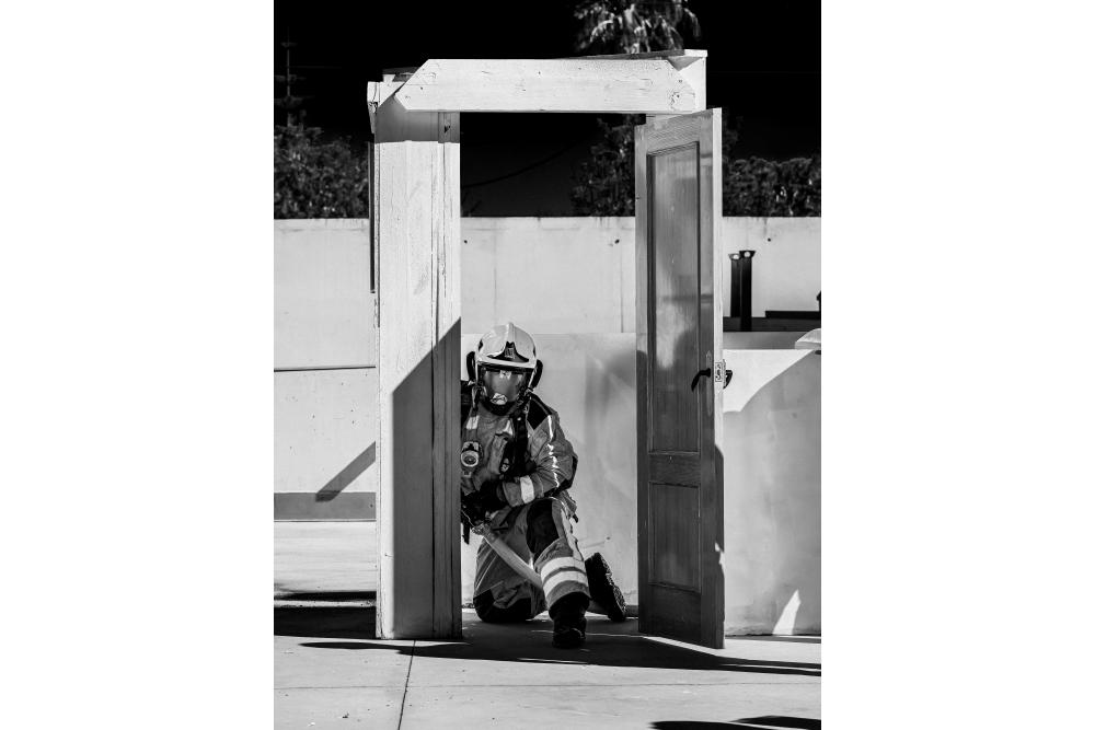 viigile del fuoco con manichetta in mano porta di legno